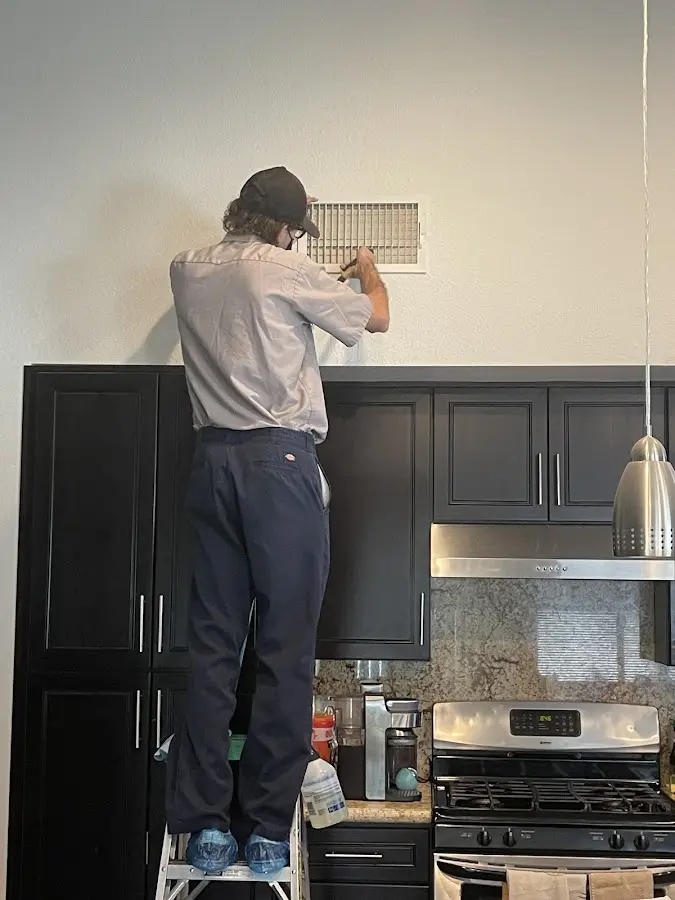 Technician inspecting an air vent during HVAC service in Fairview Park